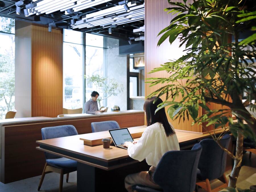A modern indoor space with a wooden table, blue chairs, and a laptop.