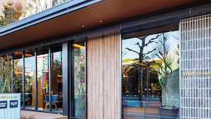 A modern building with large glass windows, a wooden ceiling, and a sign reading "&Here Tokyo Ueno Cafe". - &Here TOKYO UENO (Tokyo)