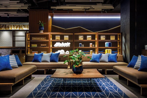 A modern library with sofas and a central table, surrounded by bookshelves.