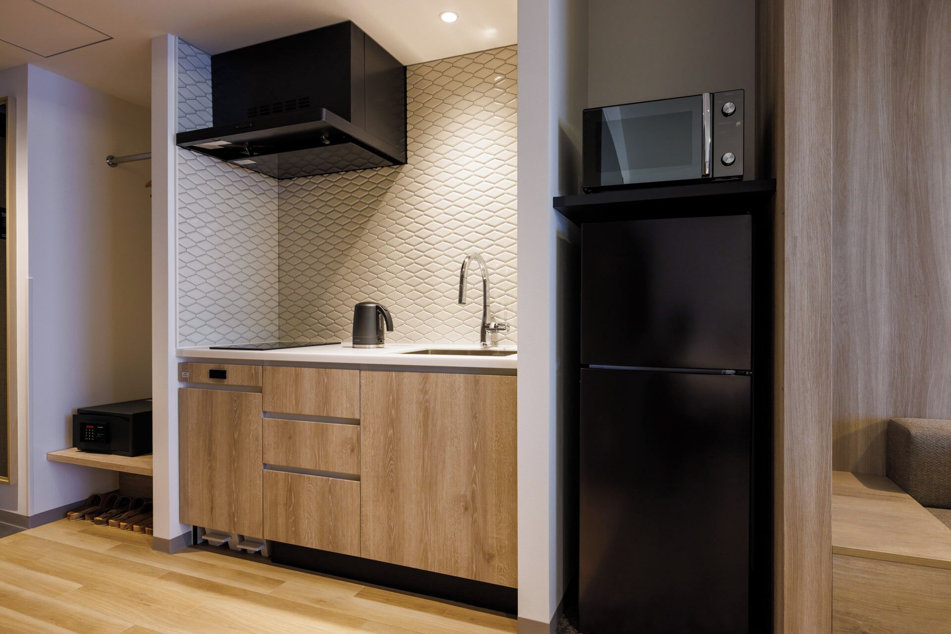 Una cocina moderna con un microondas negro, un lavamanos de acero inoxidable y armarios de madera.