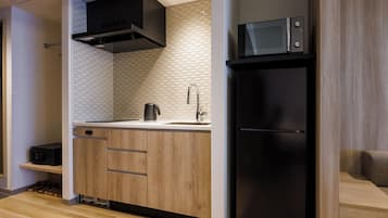 Una cocina moderna con un microondas negro, un lavamanos de acero inoxidable y armarios de madera.