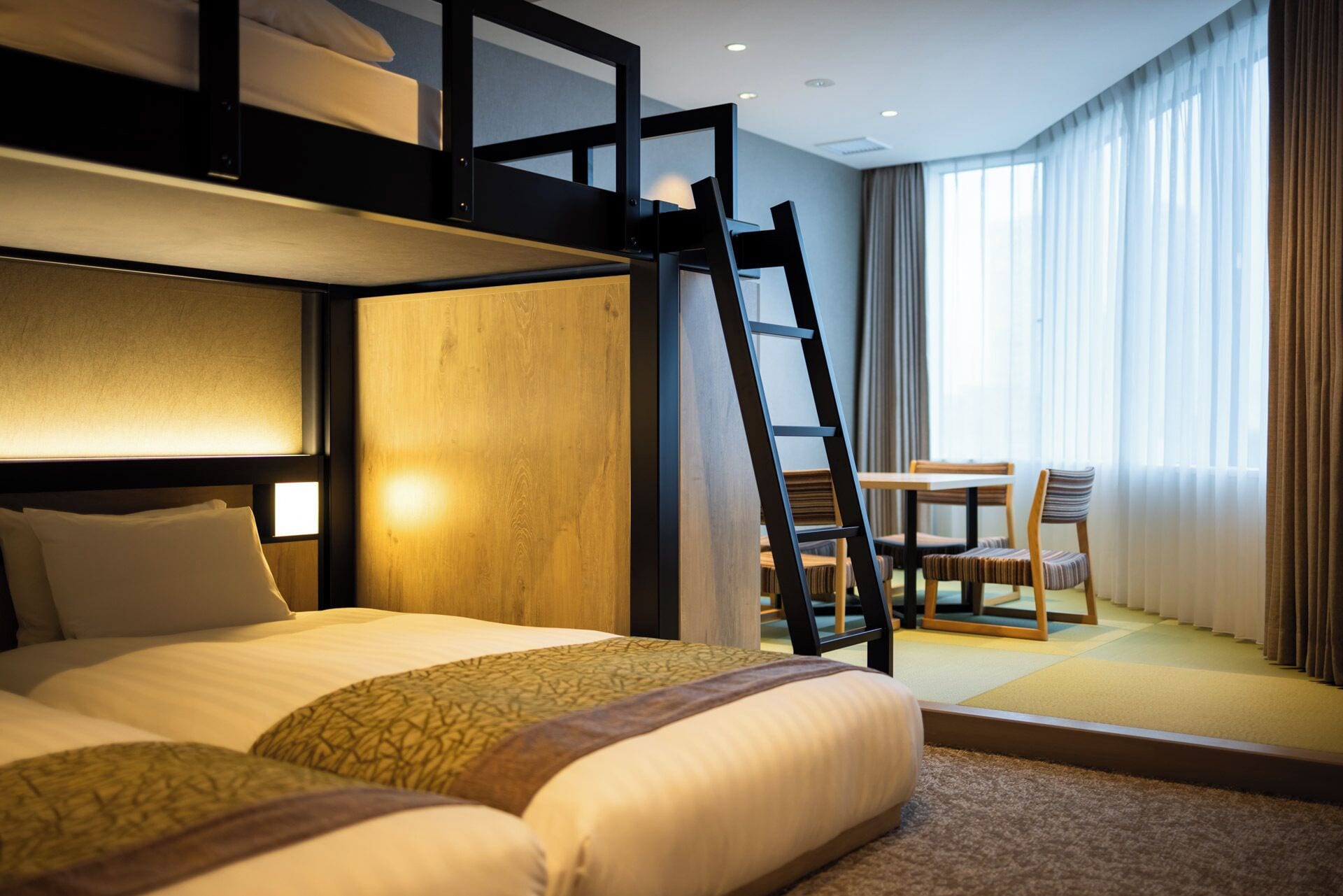 Et hotelværelse med køjeseng, et skrivebord og en stol.