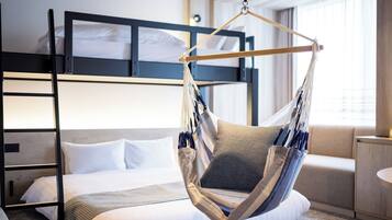 A modern hotel room with a bunk bed, a hanging chair, and a sofa.