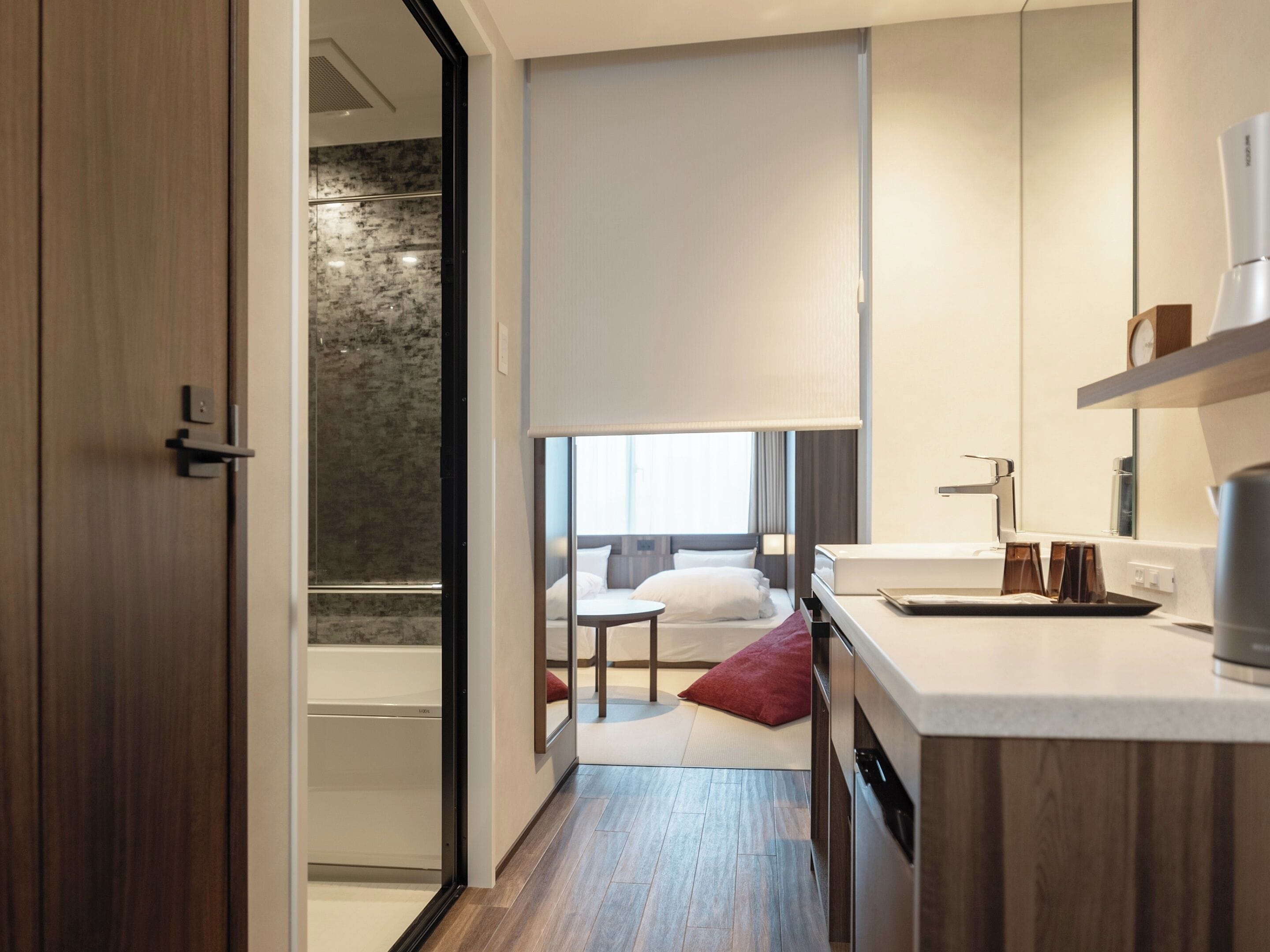 Habitació d'hotel moderna amb terra de fusta, llit amb roba de llit blanca, una taula petita i un bany amb banyera.