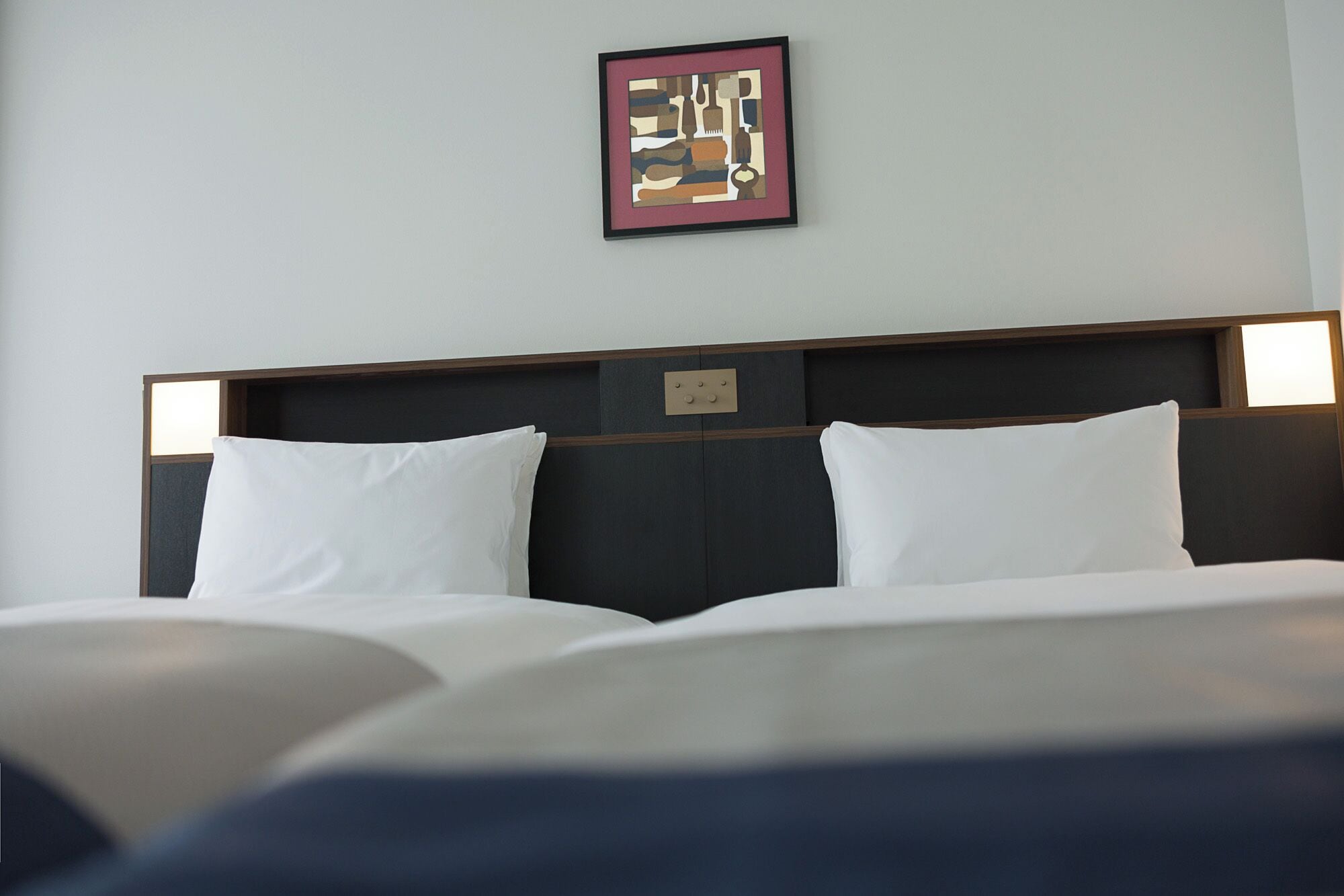 Une chambre d’hôtel avec un grand lit, deux tables de chevet avec des lampes et une œuvre d’art encadrée au mur.