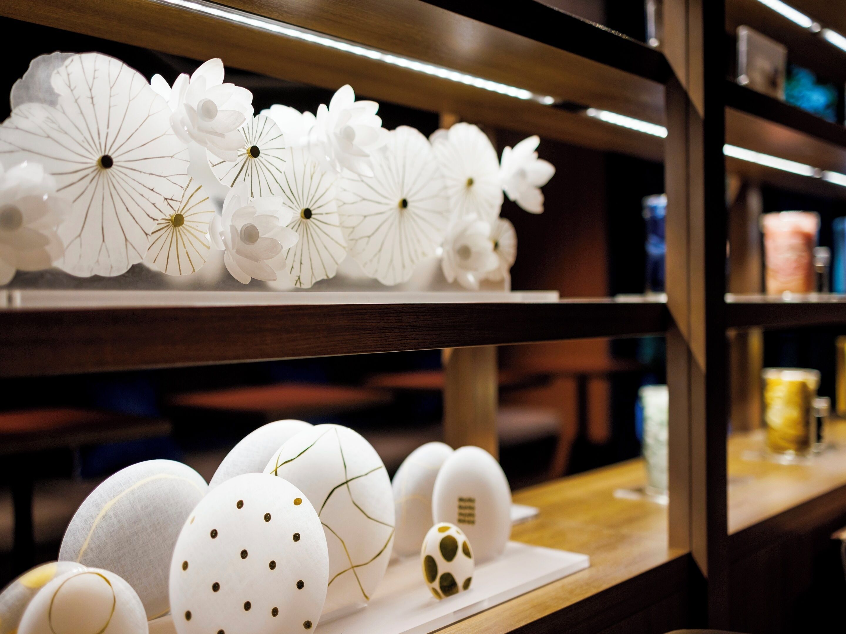 A display of white paper flowers and decorated eggs on shelves.