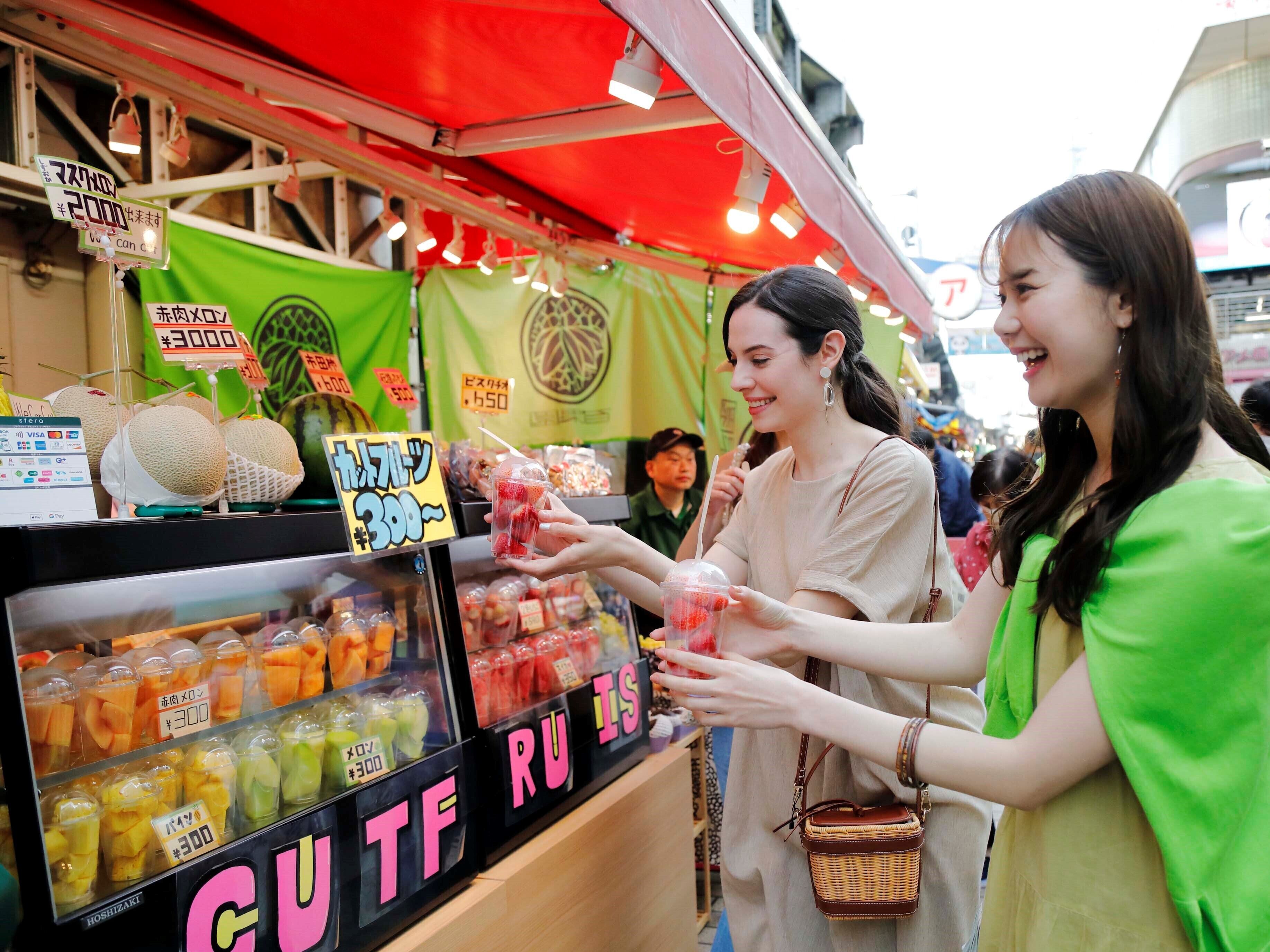 A fruit stand with various fruits and drinks for sale.