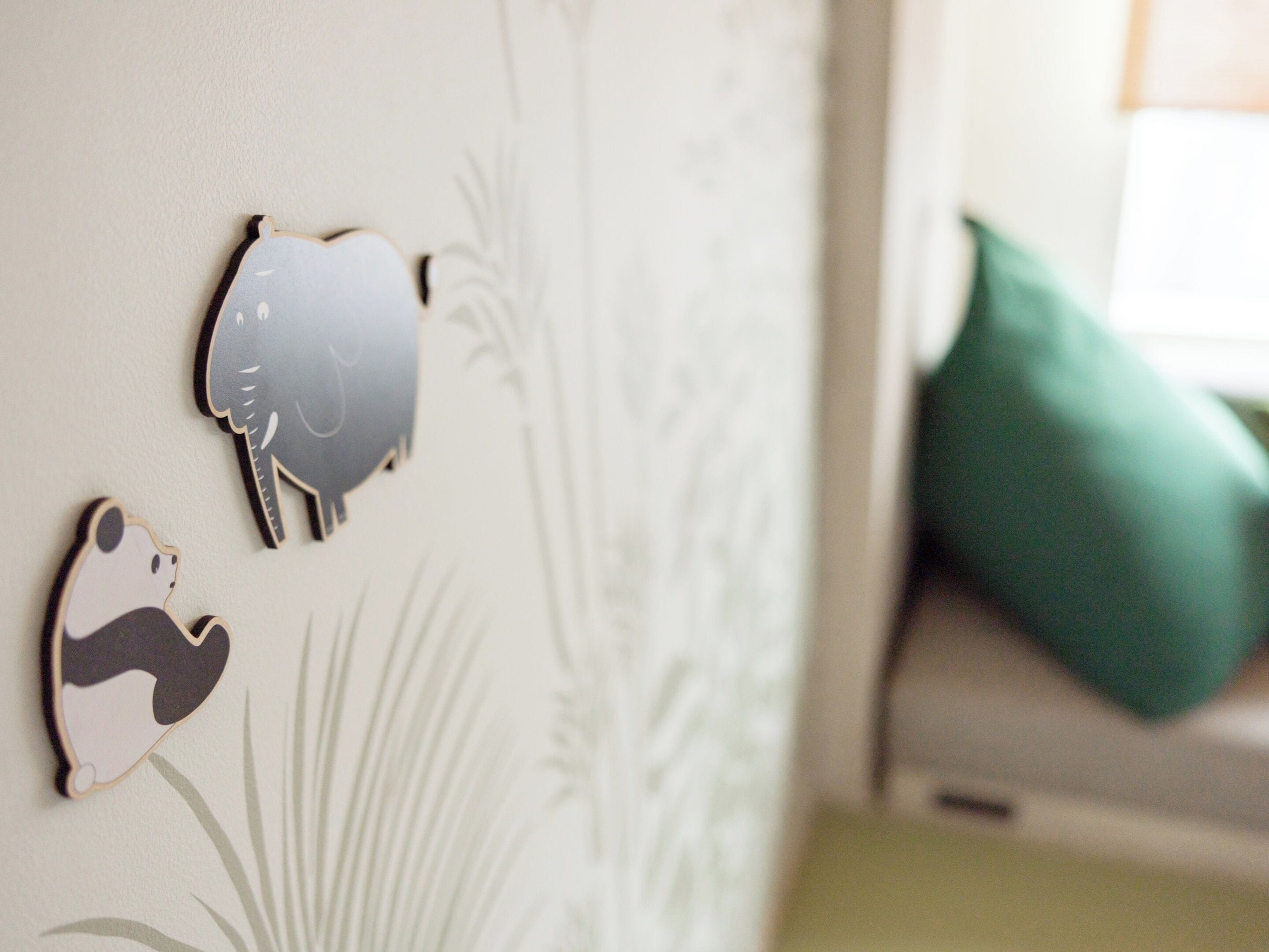 A wall with decorative animal cutouts and a green pillow on a couch.