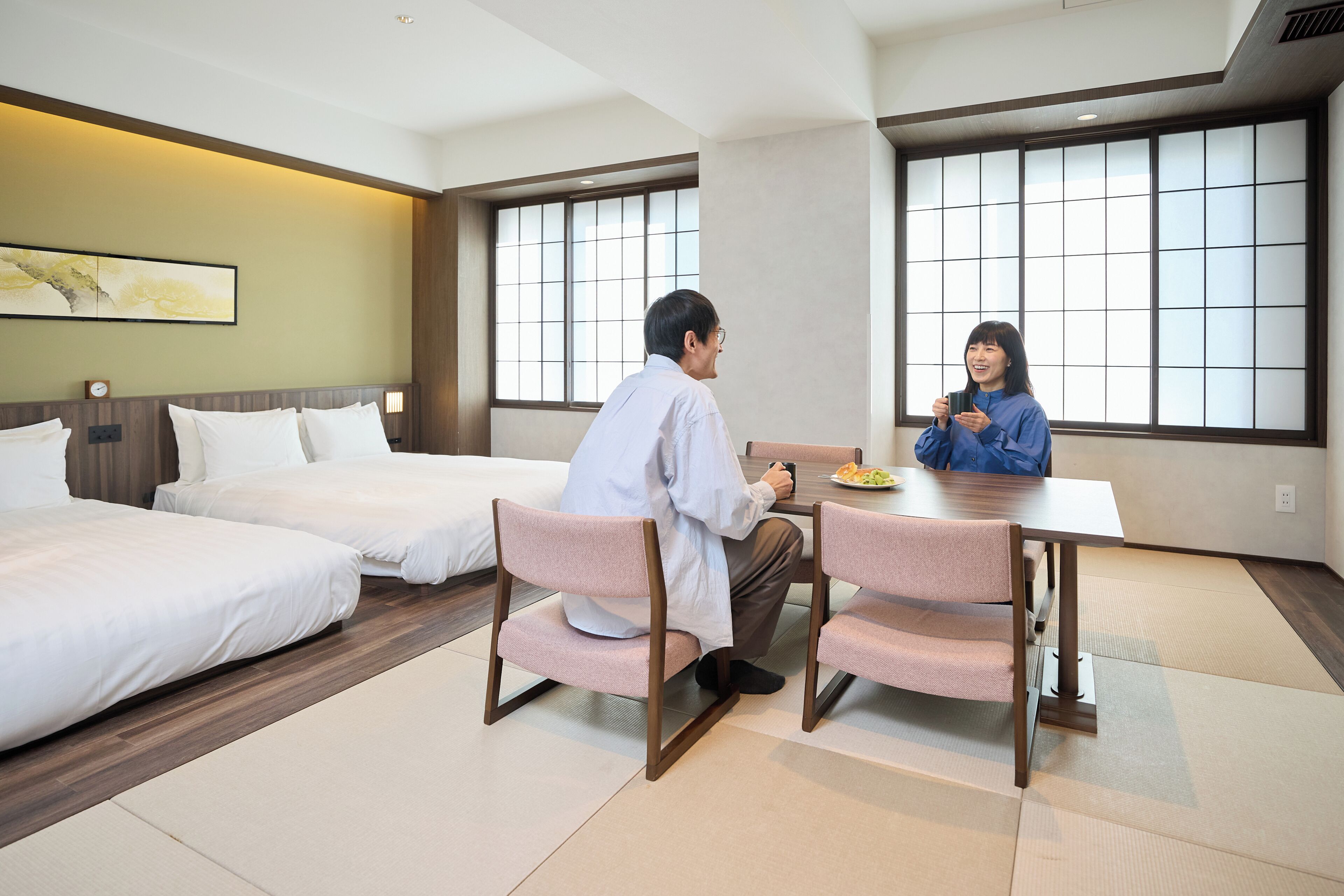 Ein Hotelzimmer mit zwei Betten, einem Esstisch und Tatami-Matten.