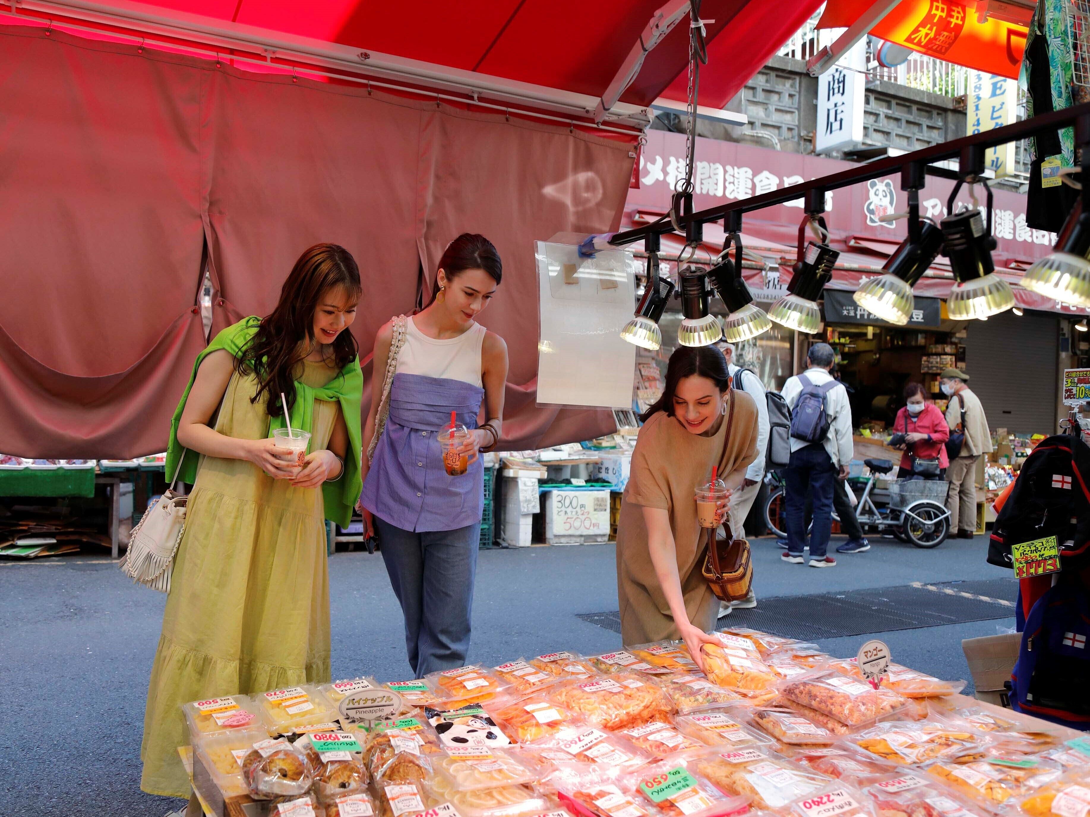 Un puesto de mercado con diversos productos envasados y un toldo rojo.