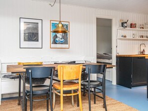 A dining area with a wooden table, black chairs, and a yellow chair. There are two framed artworks on the wall.