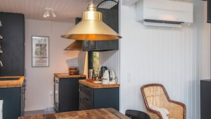 A modern kitchen with a wooden table, a hanging pendant light, and a wicker chair. - 6 Person Holiday Home in Ebeltoft-by Traum (Ebeltoft)