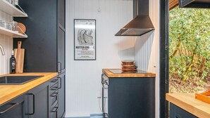 A compact kitchen with a black countertop, wooden cabinets, and a stainless steel range hood. - 6 Person Holiday Home in Ebeltoft-by Traum (Ebeltoft)