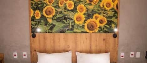 Un dormitorio con una cama grande, ropa de cama blanca y un mural de girasoles en la pared.