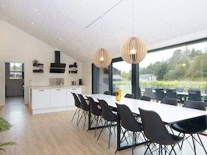 A modern kitchen with white cabinetry, a central island, and pendant lighting. - 5 Star Holiday Home in Ebeltoft (Ebeltoft)