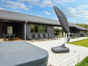 A modern building with a tiled roof, outdoor seating with chairs and tables, and a covered area with a table and chairs. - 5 Star Holiday Home in Ebeltoft (Ebeltoft)