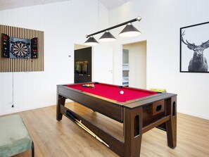 A pool table with a red felt surface, a dartboard, and a framed animal picture on the wall. - 5 Star Holiday Home in Ebeltoft (Ebeltoft)