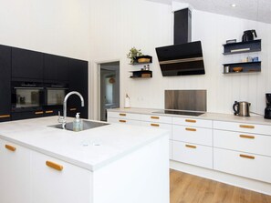 A modern kitchen with black and white cabinetry, a stainless steel sink, and a built-in oven.