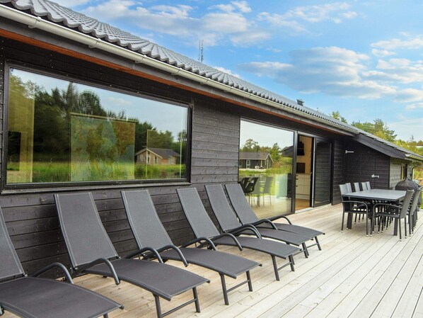 A modern outdoor deck with lounge chairs and a dining table.