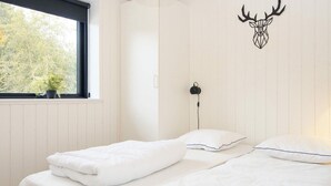 A bedroom with two beds, a window with a view of trees, a wall-mounted deer head decoration, and a bedside table with a lamp. - 14 Person Holiday Home in Ebeltoft-by Traum (Ebeltoft)