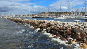 A marina with boats docked, a rocky breakwater, and a clear sky. - 14 Person Holiday Home in Ebeltoft-by Traum (Ebeltoft)