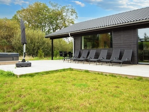 A modern building with a flat roof, a covered outdoor seating area with chairs, and a large window. - 5 Star Holiday Home in Ebeltoft (Ebeltoft)