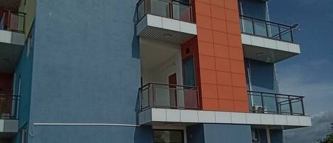 Un edificio de varios pisos con fachada azul, sección central roja y balcones.