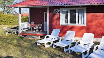 A red building with a porch, outdoor seating, and a window.