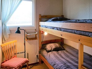 Una cama litera con escritorio y silla, una ventana con cortinas y una lámpara.