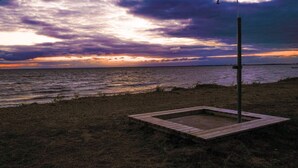 A beach with a wooden structure and a metal pole, likely a lifeguard stand, under a cloudy sky. - 5 Person Holiday Home in Morbylanga (Morbylanga)
