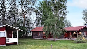 A rustic cabin-style hotel with a red roof and wooden exterior, surrounded by lush greenery and trees. - 5 Person Holiday Home in Morbylanga (Morbylanga)