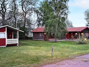 A rustic cabin-style hotel with a red roof and wooden exterior, surrounded by lush greenery and trees. - 5 Person Holiday Home in Morbylanga (Morbylanga)