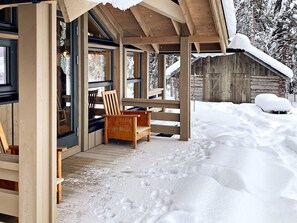 Enjoy the serene views from the cozy porch, surrounded by snow-covered woods.