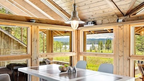 A wooden cabin interior with a dining table, chairs, and a view of a lake and forest. - 6 Person Holiday Home in Tisleidalen-by Traum (Nord-Aurdal)