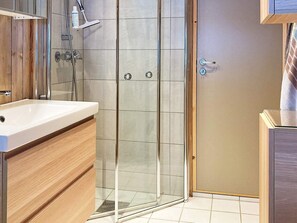 Bathroom features a glass-enclosed shower, handheld showerhead, and wall-mounted faucet.