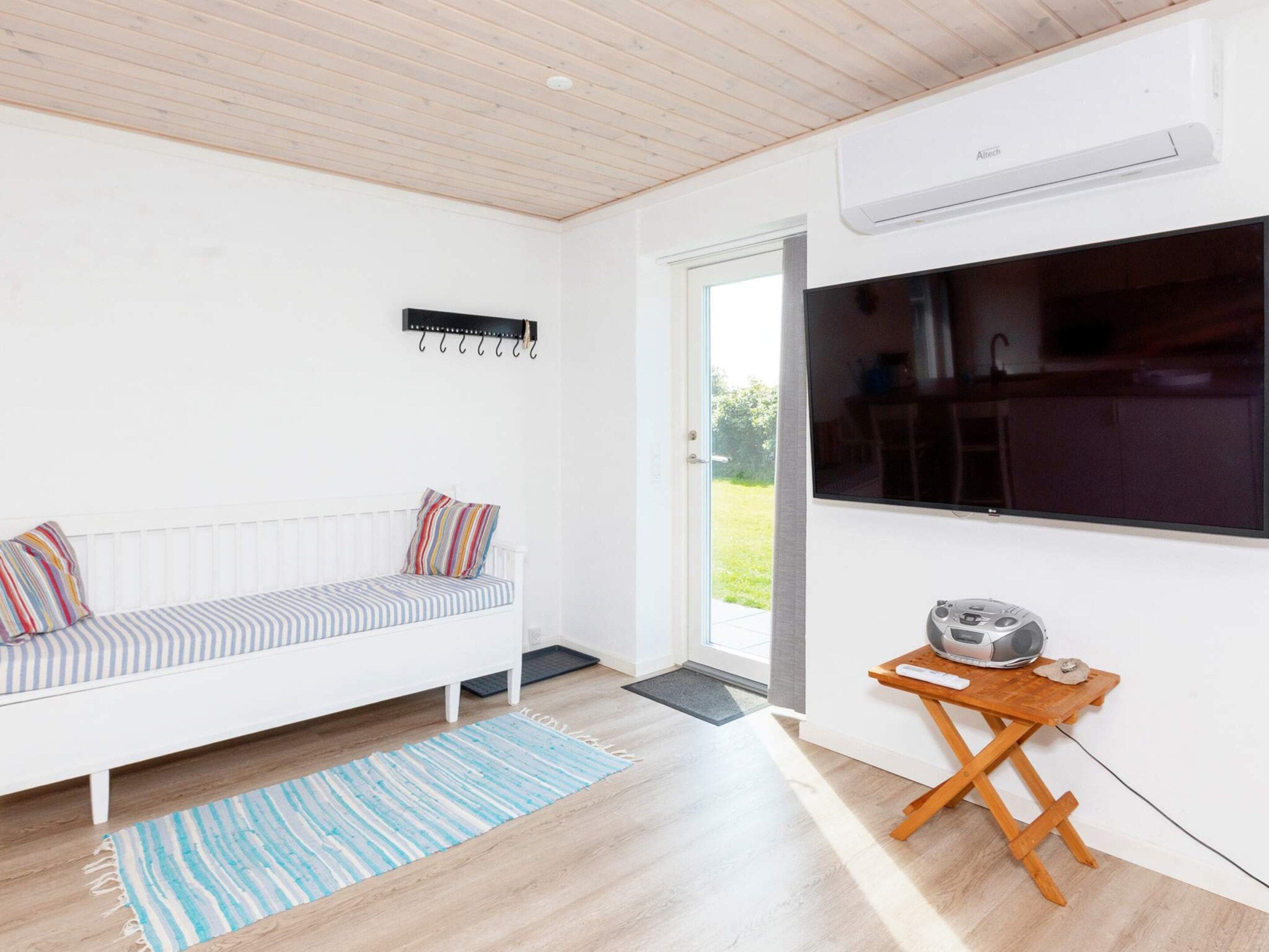 A modern room with a white sofa, a small wooden table, and a large window.