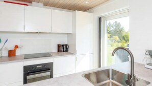 A modern kitchen with white cabinetry, a stainless steel sink, and a window providing a view of the outdoors. - 6 Person Holiday Home in Hjorring (Hjørring)