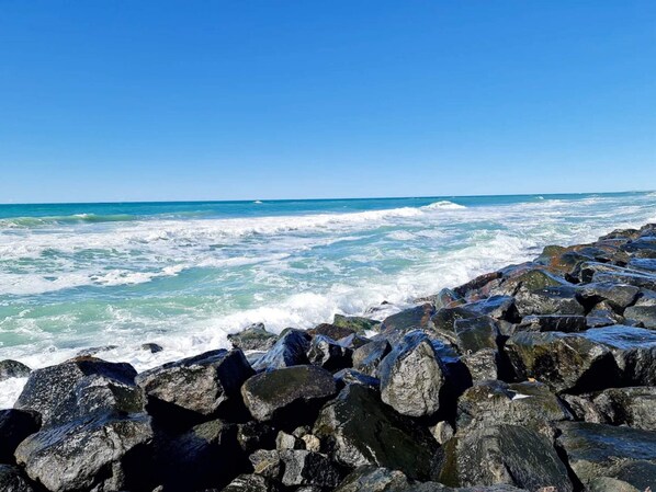 A rocky shoreline with waves crashing against the rocks under a clear blue sky. - 6 Person Holiday Home in Hjorring (Hjørring)