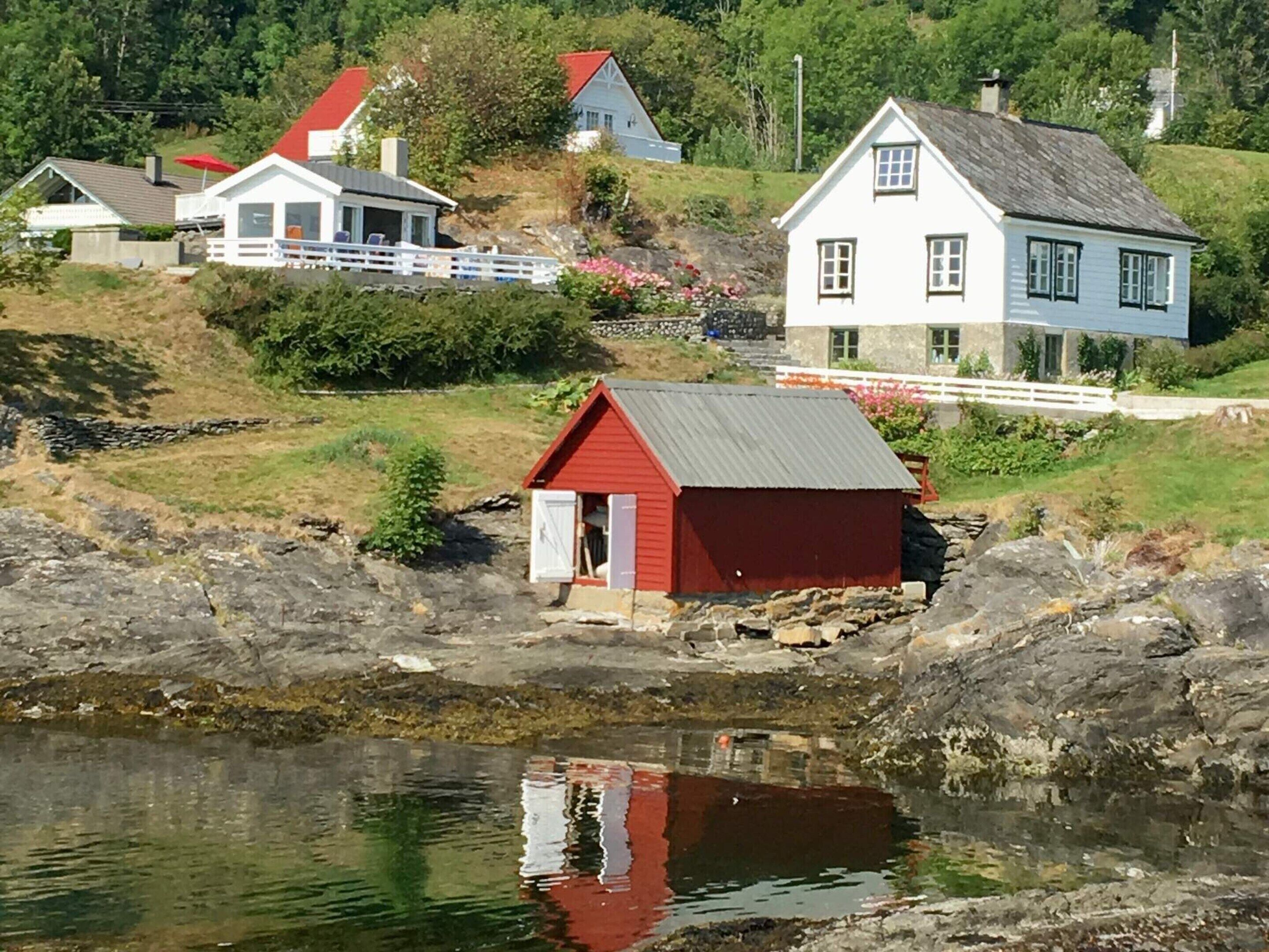 A coastal scene with a red wooden structure near a body of water, surrounded by houses with red roofs and white walls.