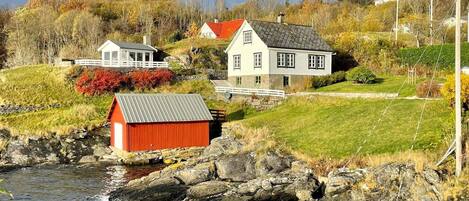 A coastal house with a red shed, a white house, and a small white building with a balcony.