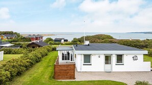 A white mobile home with a small deck, a garage, and a view of the sea. - 7 Person Holiday Home in Lemvig (Lemvig)