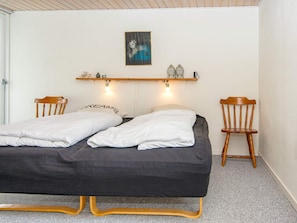A room with a bed, two chairs, a shelf with decorative items, and a painting on the wall. - 7 Person Holiday Home in Lemvig (Lemvig)