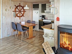 Una cocina acogedora con una mesa de madera, sillas, una estufa y una chimenea.