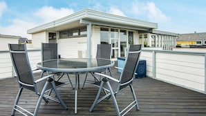 A rooftop terrace with a glass table and metal chairs, overlooking a residential area. - 7 Person Holiday Home in Lemvig (Lemvig)
