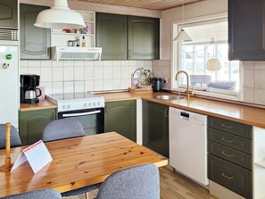 A compact kitchen with a stove, sink, and dishwasher. There is a window providing natural light and a view outside. - 7 Person Holiday Home in Lemvig (Lemvig)