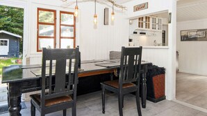 Een eetruimte met een houten tafel en stoelen, een hanglamp en uitzicht op het buiten.