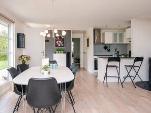A modern kitchen with a dining area, featuring a large island, black chairs, and a white table. - 6 Person Holiday Home in Ebeltoft (Ebeltoft)