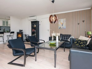 A modern living room with a glass coffee table, black leather sofa, and a fireplace. - 6 Person Holiday Home in Ebeltoft (Ebeltoft)