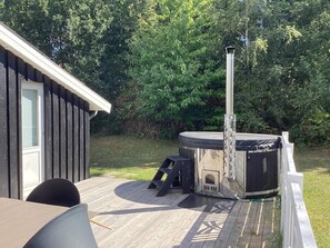 A hot tub on a wooden deck with a metal chimney, a small table, and chairs. - 6 Person Holiday Home in Ebeltoft (Ebeltoft)