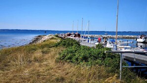 En lysthavn med fortøjede både, en træpromenade og frit udsyn til vandet.